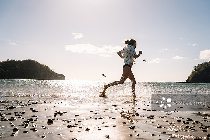 穿着夏装的女人奔向大海的边缘，哥斯达黎加图片素材