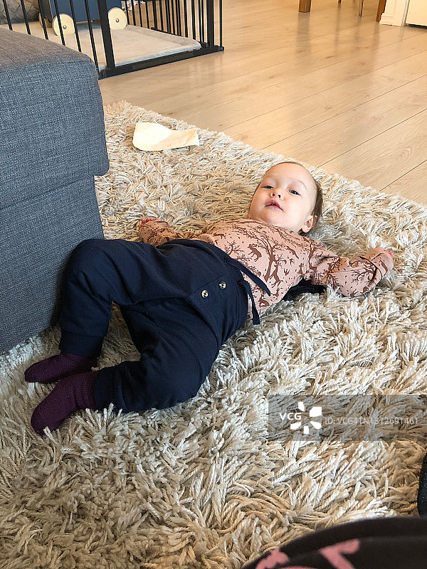 儿童躺在家中时尚的地毯上图片素材