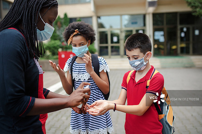 母亲给返校的孩子消毒双手图片素材
