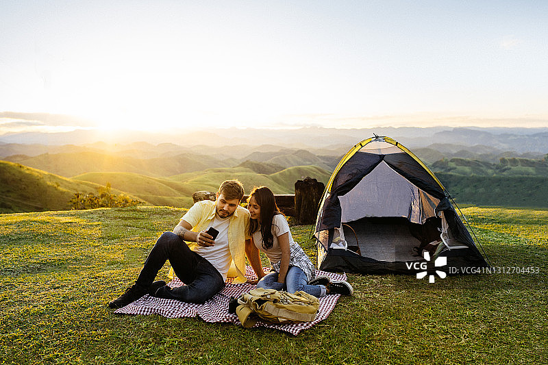 情侣在日落时分在山中露营图片素材
