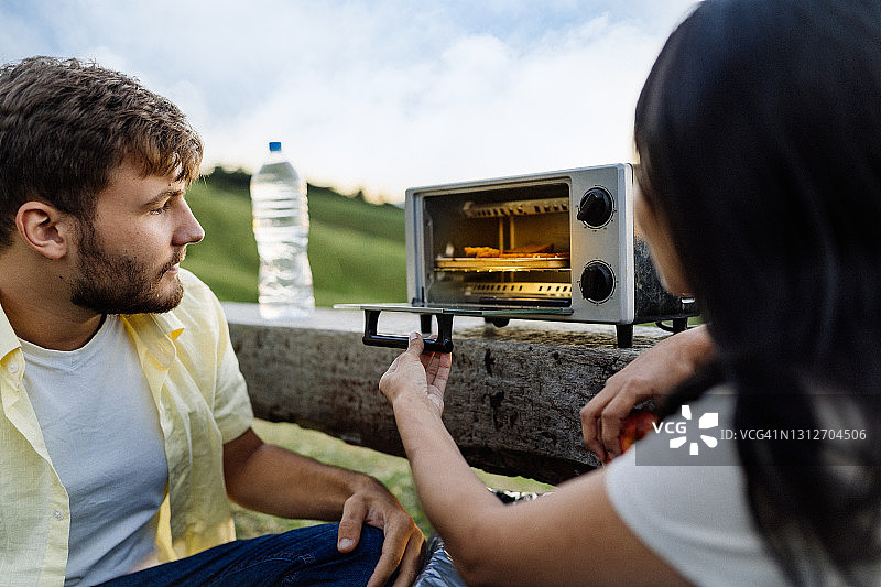 情侣在露营区使用电烤箱图片素材