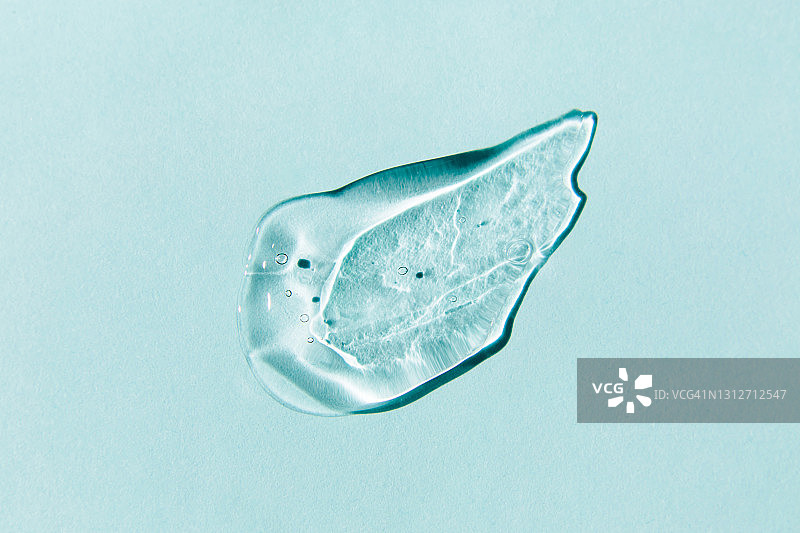 蓝色背景上的透明凝胶涂抹，液态透明质酸凝胶图片素材