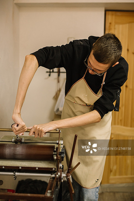 一个在工作室里工作的年轻男人，在机器旁工作图片素材