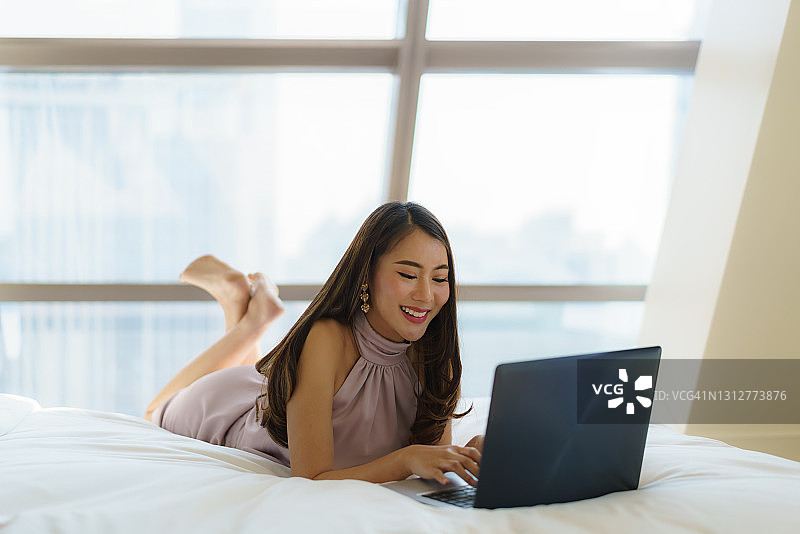亚洲女性在豪华酒店使用笔记本电脑工作或与朋友聊天图片素材