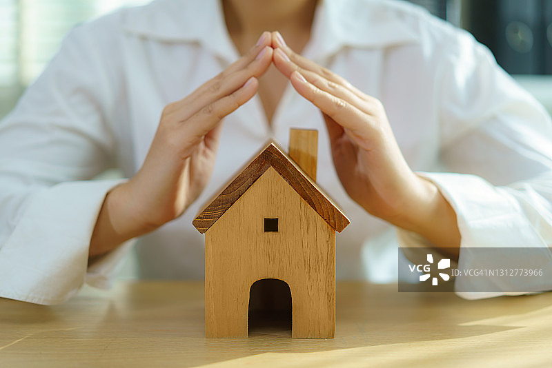 保护性商业女性之手呵护房屋，房屋和房地产保险概念图片素材