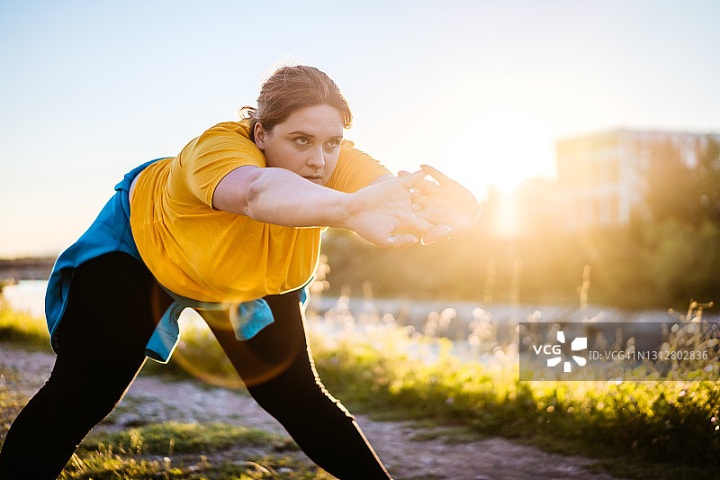 在户外伸展身体的超重年轻女人图片素材