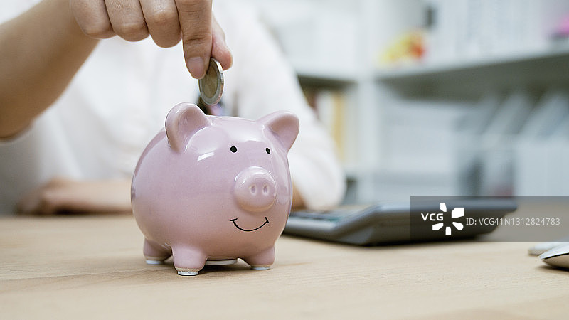 女人手把硬币放入存钱罐里存钱图片素材