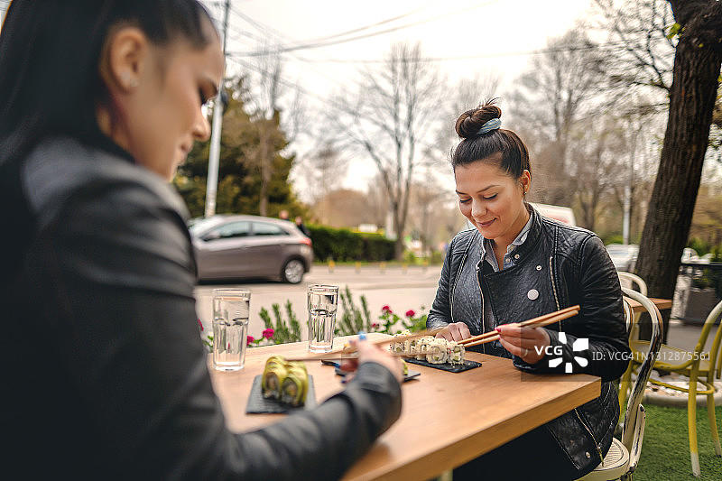 坐着吃寿司的两位年轻女性图片素材