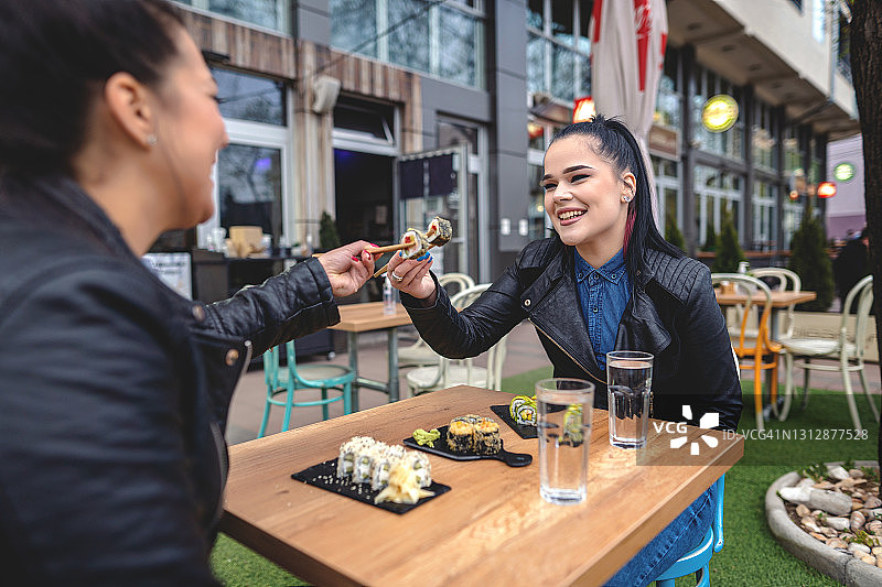 坐着吃寿司的两位年轻女性图片素材