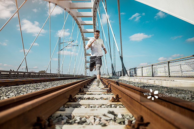 在铁路上奔跑的快乐年轻运动员图片素材