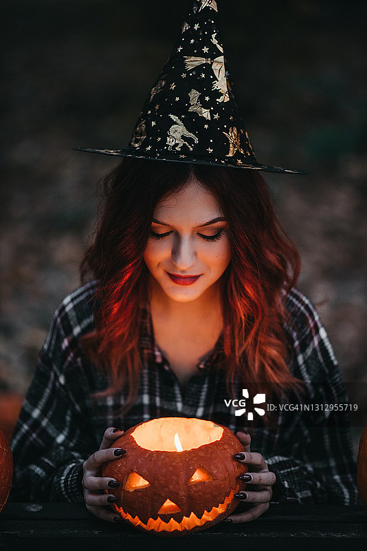 年轻女巫手持弯曲南瓜图片素材