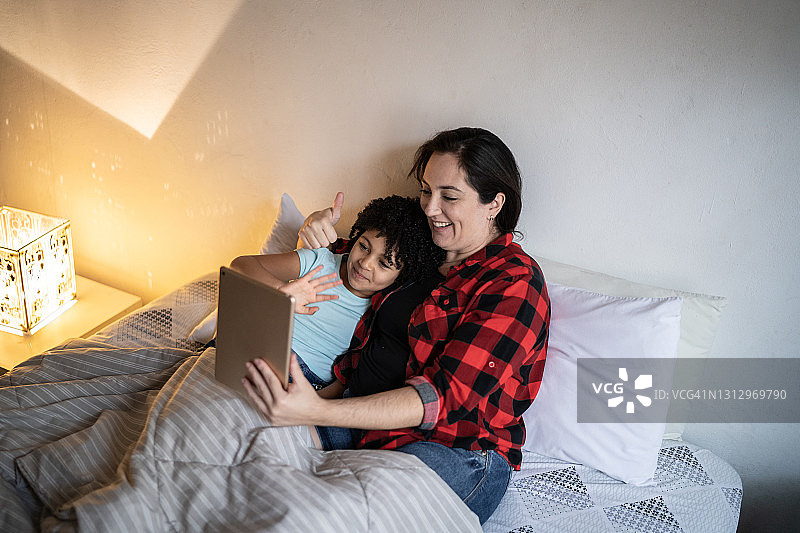 母女在床上用平板电脑进行视频通话图片素材