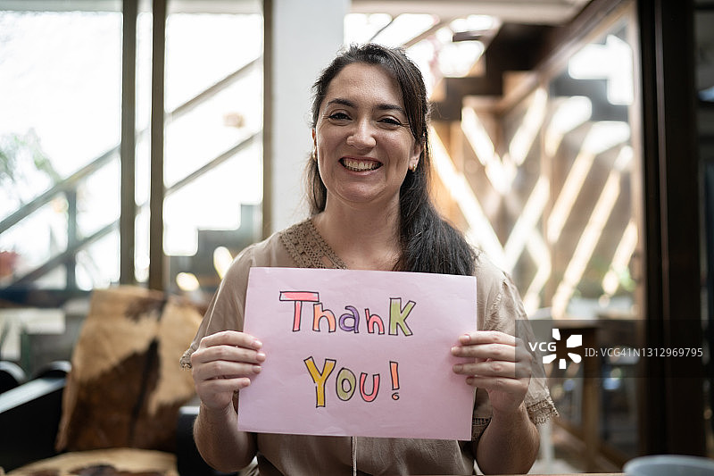 在家中手持写有“谢谢你”字样的纸张的女人图片素材