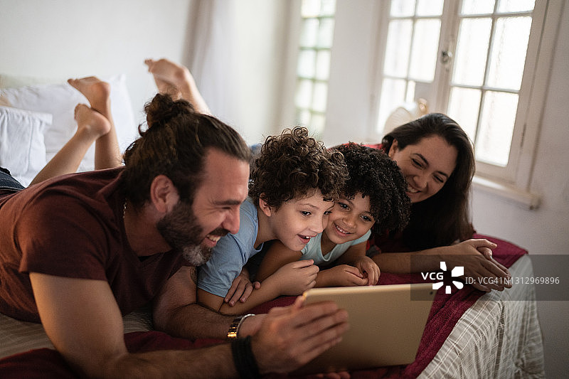 在床上用平板电脑观看节目的家庭图片素材