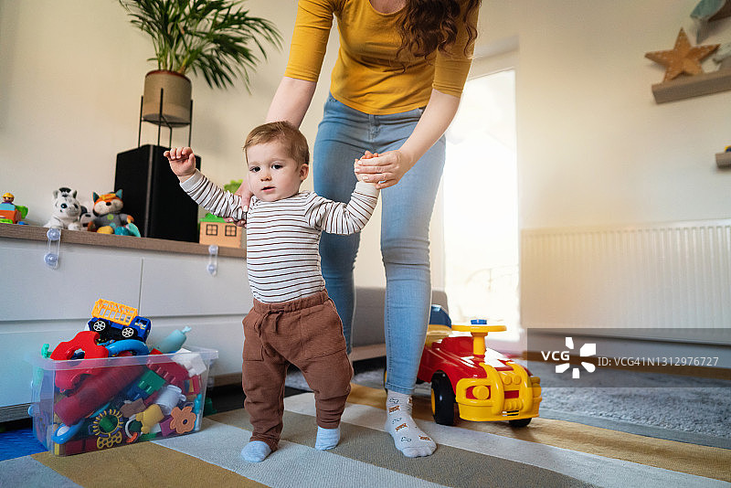 在看不清样子的妈妈的帮助下，小男孩迈出人生的第一步图片素材