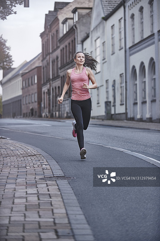 在城市里跑步的年轻粉衣女子图片素材
