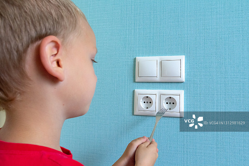 儿童安全警示：好奇的孩童用叉子捅电源插座图片素材