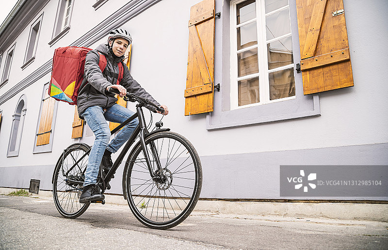 年轻快递员骑自行车在城市里送餐图片素材