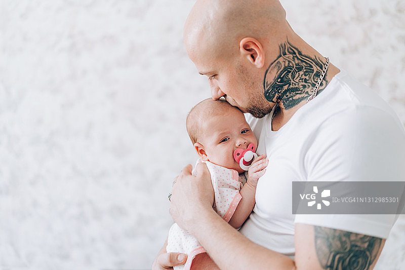年轻父亲抱着新生儿，表现父爱与关怀图片素材