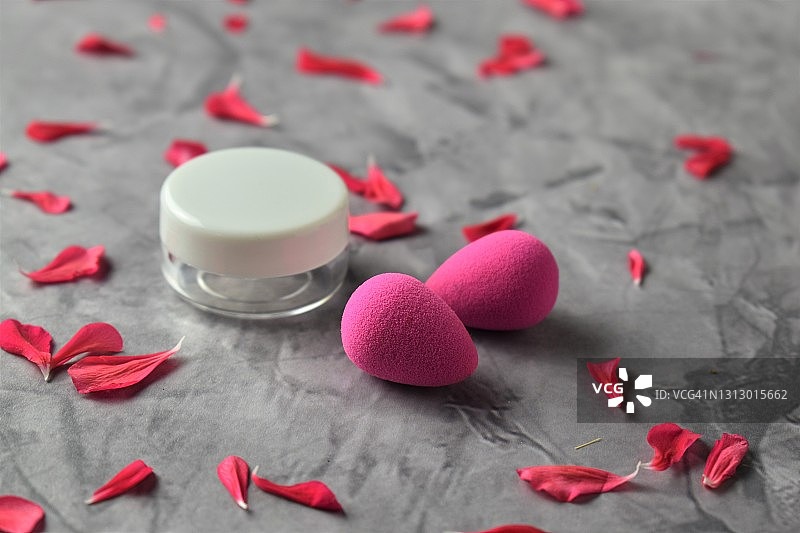 质朴背景上带有花瓣的洁面霜和化妆海绵图片素材