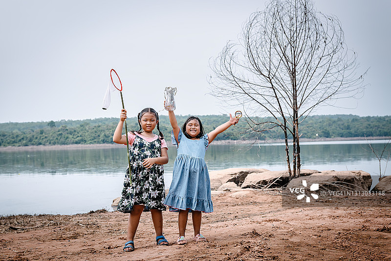 在湖边花园拿着捕捉蝴蝶设备的两个小女孩 портрет.  科学与教育探索摄影主题图片素材