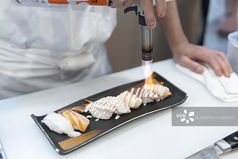 厨师正在用喷枪烤制生鱼片寿司图片素材