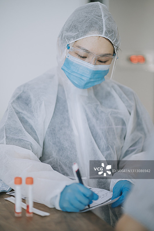 中国女医生穿着防护服为病人记录信息填写新冠检测表格图片素材