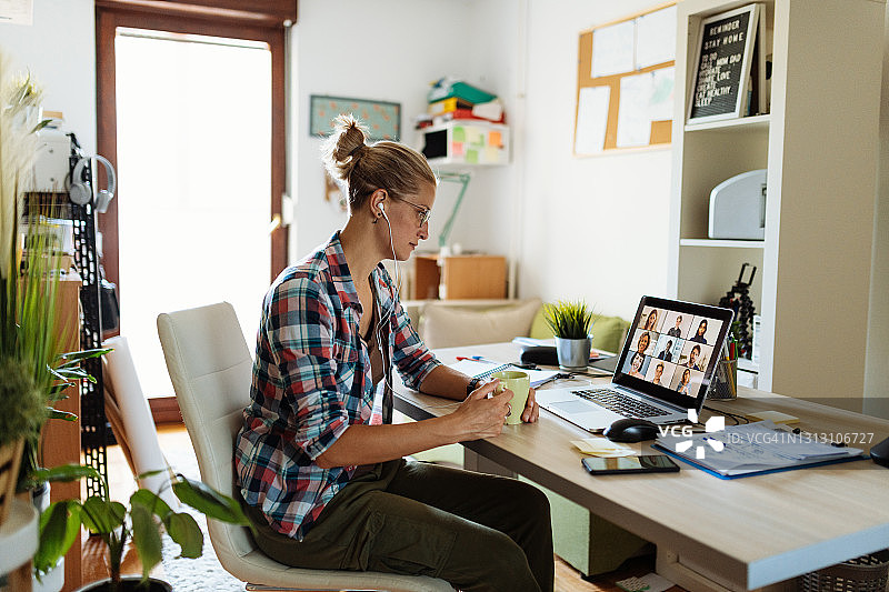 在家中使用笔记本电脑进行视频通话和远程办公的严肃女商人图片素材