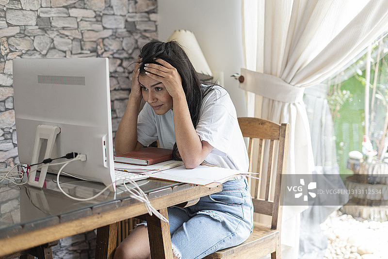 年轻女人在家用电脑工作，对所做的一切工作感到压力和绝望图片素材