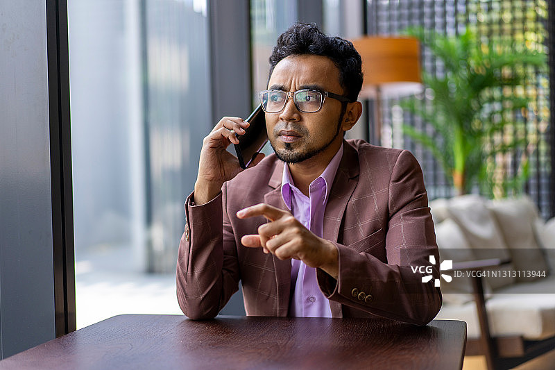 年轻的亚裔马来商人专注地用手机交谈图片素材