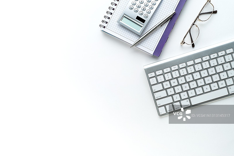 笔、计算器、眼镜和打开的笔记本，在笔记本电脑或键盘旁边。记录商人或会计师信息的笔记本，财务报告的概念，计算业务的损益，维护费用和收入。图片素材