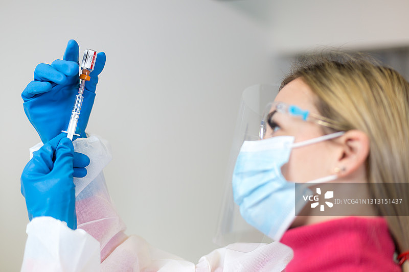年轻女医务人员从药瓶中抽取新冠疫苗图片素材