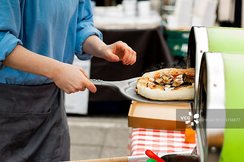 一位年轻人在户外市场经营披萨摊位图片素材