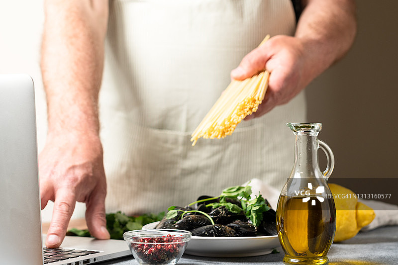 男人根据在线虚拟大师班教程烹饪海鲜意大利面图片素材