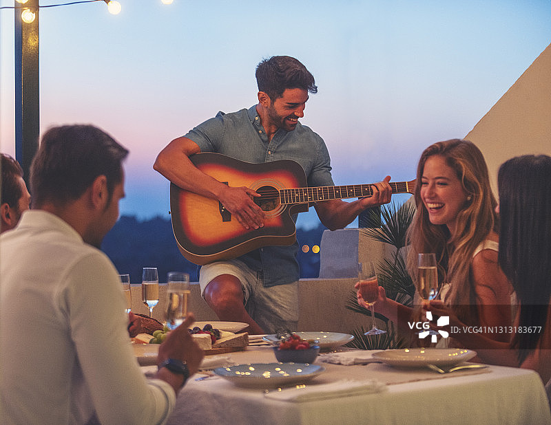 一群朋友举办晚宴，一位男士在弹吉他图片素材