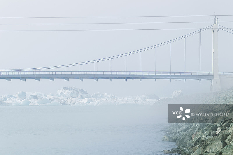 冰岛斯卡夫塔费尔冰川上的冰川蓝色泻湖Jokulsarlon的公路桥。雾蒙蒙的冬季天气。图片素材