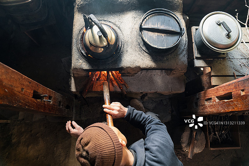 一位年长的日本男人对着燃木炉吹气生火的鸟瞰图图片素材