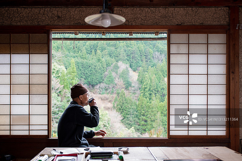 年长的日本艺术家喝茶并眺望窗外图片素材