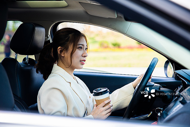 手持咖啡杯开车的年轻女性图片素材