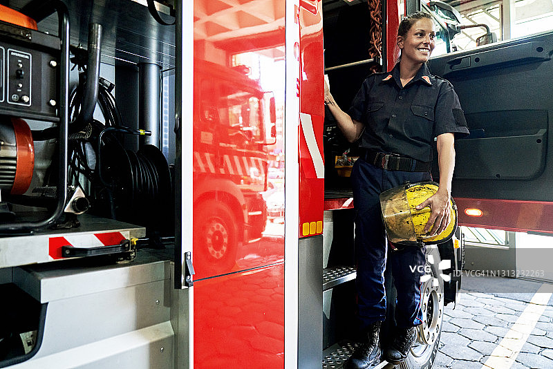 30多岁女性消防员登上消防车肖像图片素材