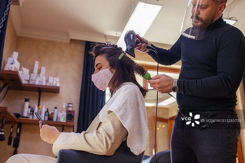 理发师用吹风机和圆梳吹干头发图片素材