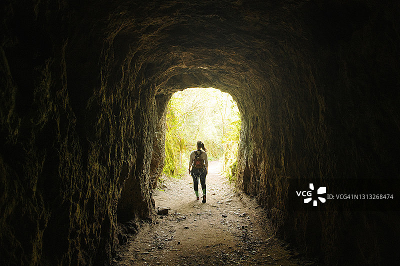 年轻女子在森林隧道中行走图片素材