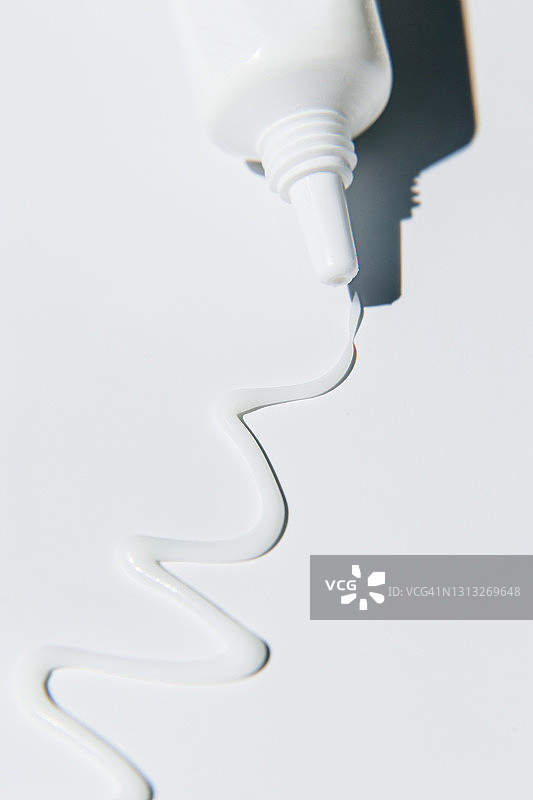 白色美容霜从管中挤出，在白色背景上。 扁平放置，顶视图，复制空间。图片素材