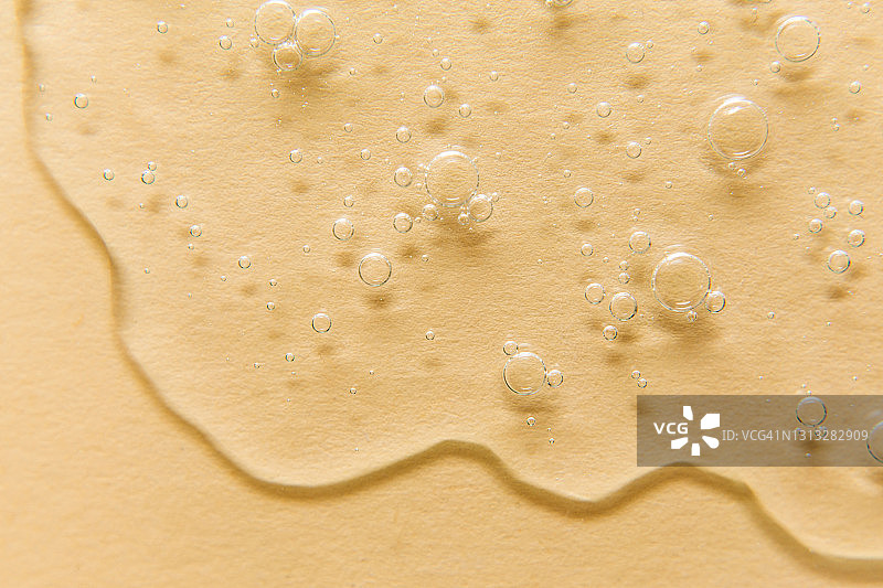 米色背景上带有气泡的透明凝胶特写，凝胶霜的质地，透明质酸凝胶图片素材