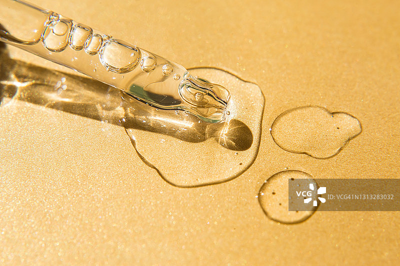 亮黄色背景上滴管附近的液体凝胶和精华液滴图片素材