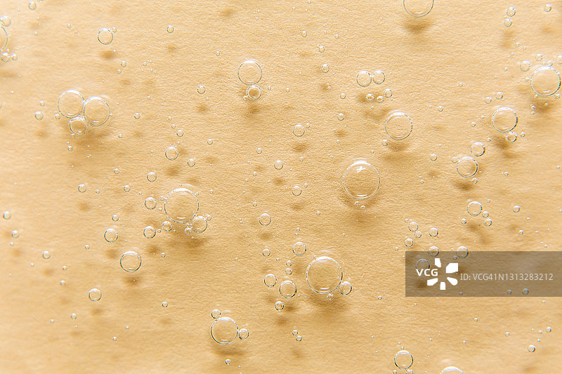 米色背景上带有气泡的透明凝胶特写，凝胶霜的质地，透明质酸凝胶图片素材