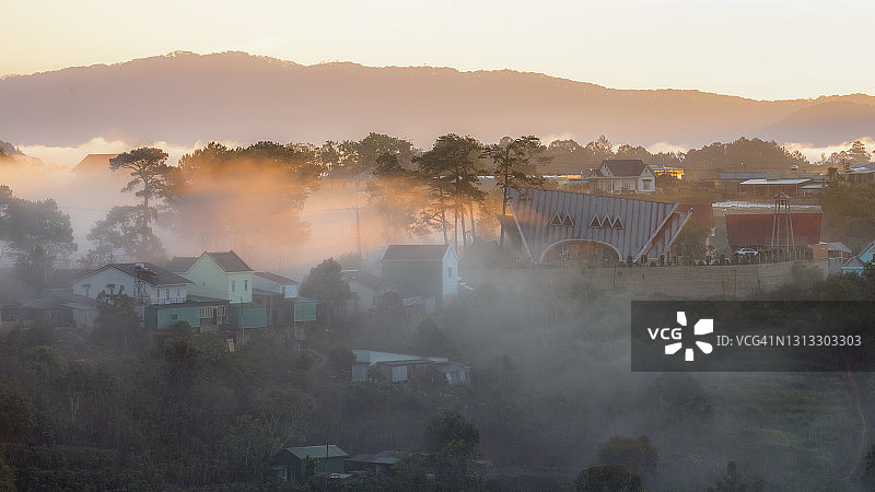 日出时山谷小屋被雾气笼罩的壮丽景色图片素材