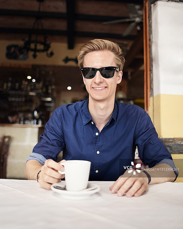 在餐厅前喝咖啡的年轻男人图片素材
