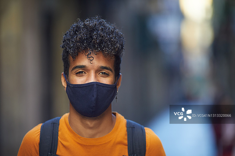街上戴着防护口罩微笑的年轻男人图片素材