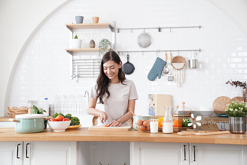 站在厨房里切胡萝卜做饭的美丽女人图片素材